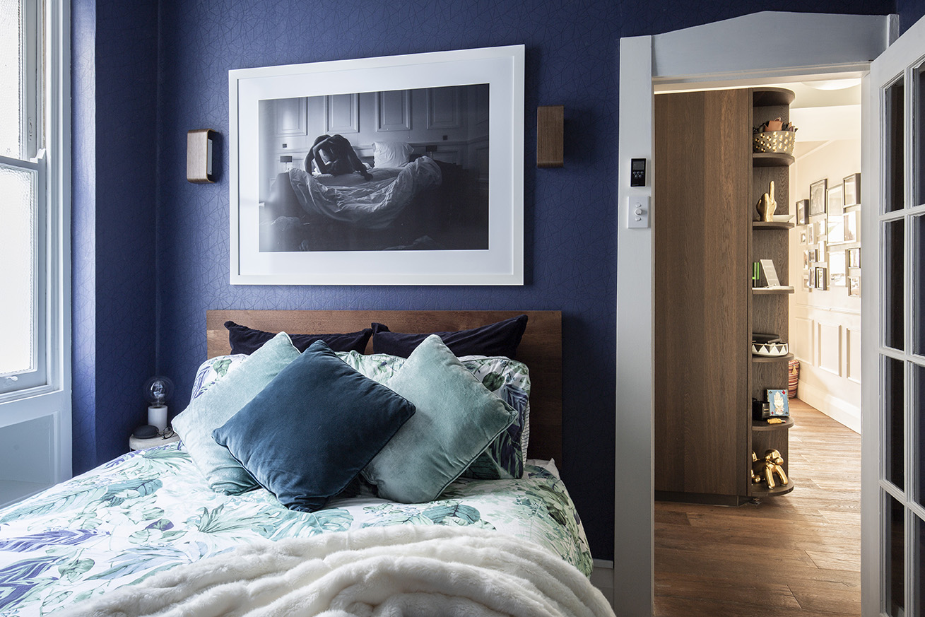 A bedroom with blue walls and a large photo on the wall.