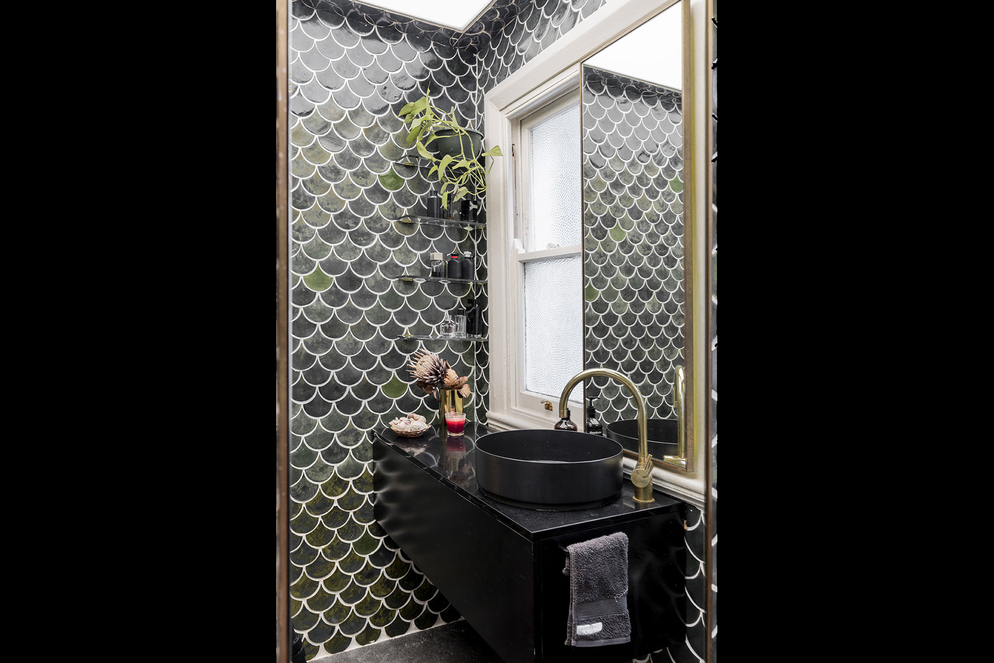 A bathroom with black tile and a sink.